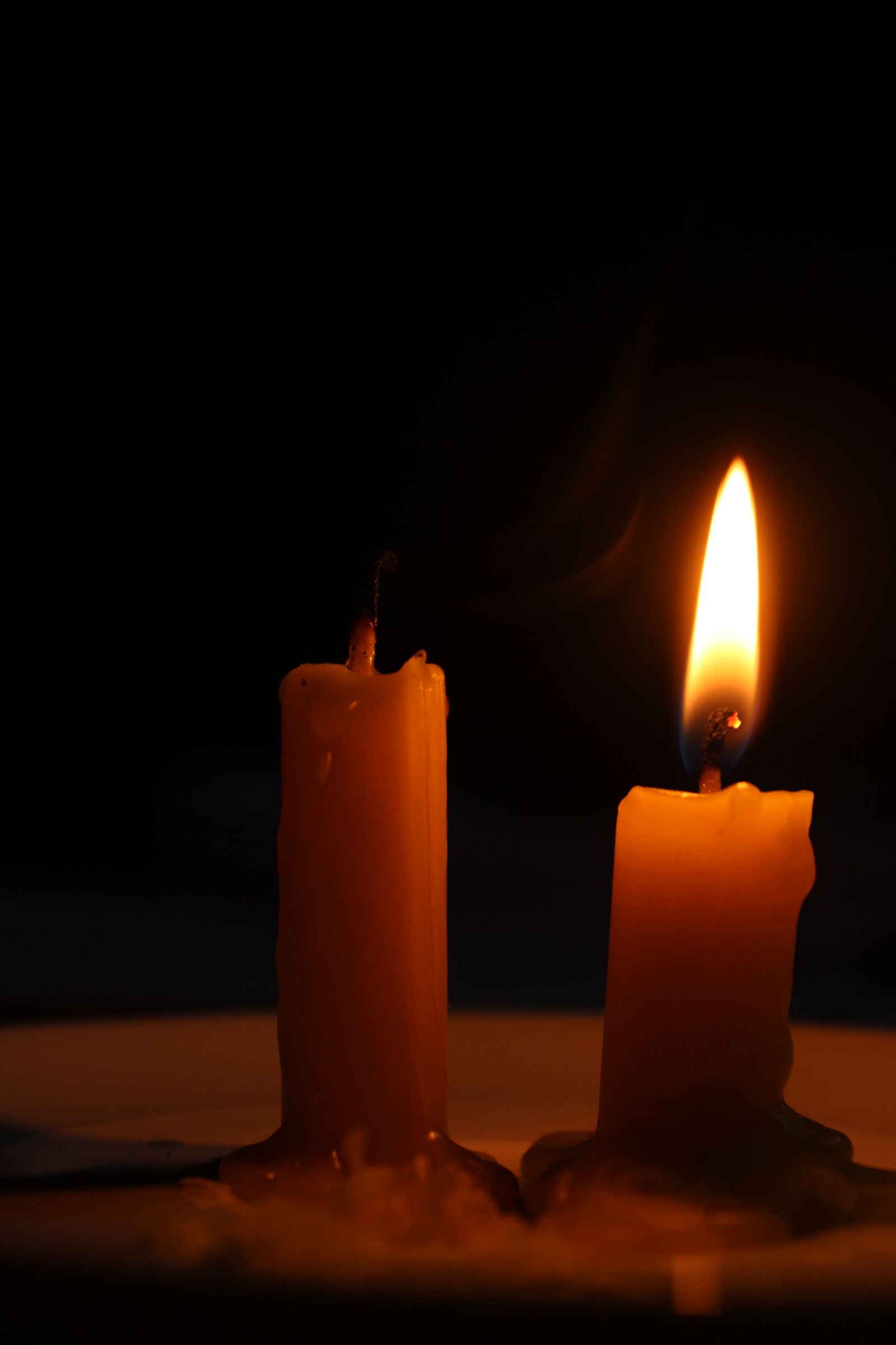Due candele su fondo nero, una accesa